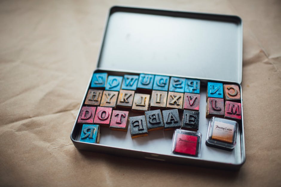 A set of colorful alphabet stamps and ink pads displayed in a metal box on a table.