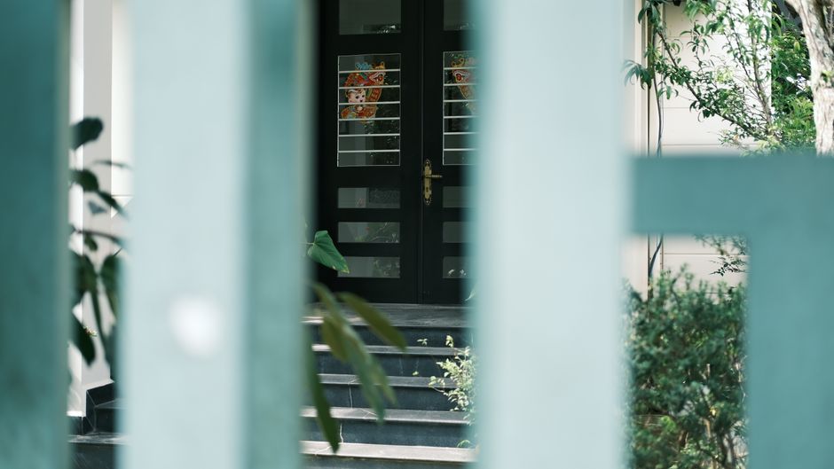 A sophisticated entrance view through gates with lush greenery around, exuding mystery and allure.